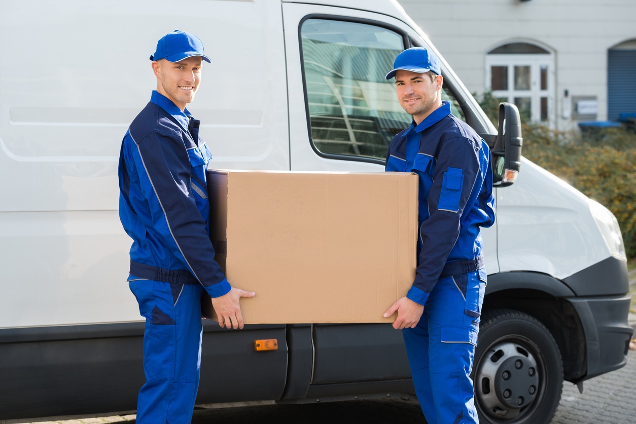Delivery Men Carrying Cardboard Box Against Truck